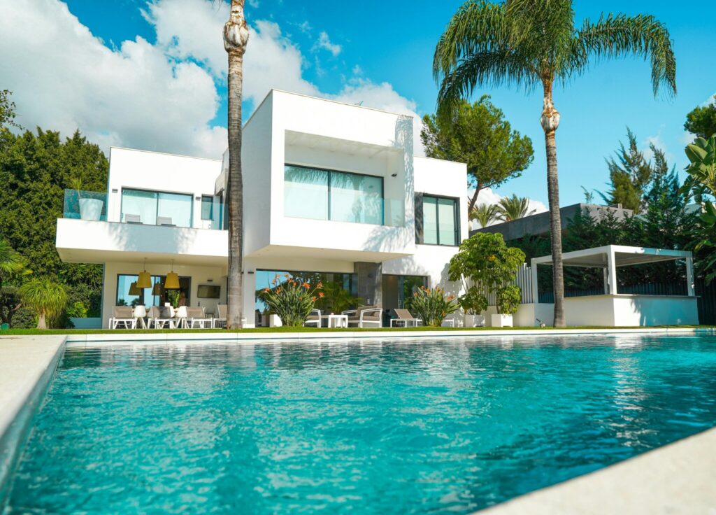 Modern white luxury home with pool and palm trees representing high-end real estate by Daryl Judy Washington Fine Properties